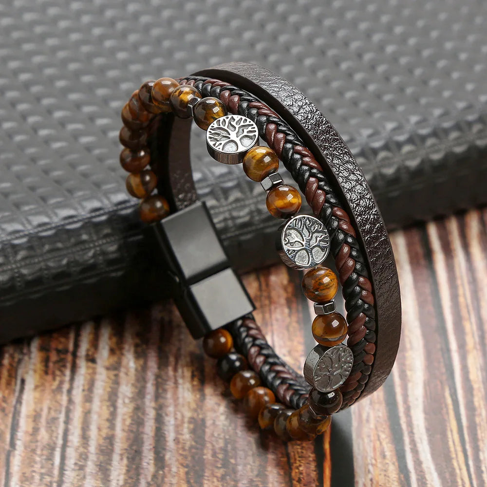 A men's multi-layer leather bracelet featuring tiger eye beads and silver accents, resting on a dark surface.