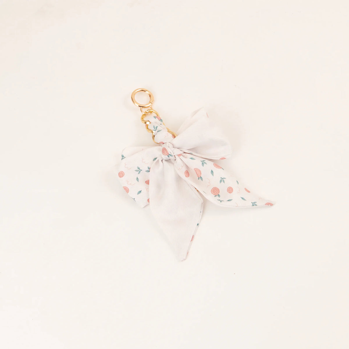 Lazo de seda blanca con patrón floral delicado, unido a un anillo de llavero dorado.