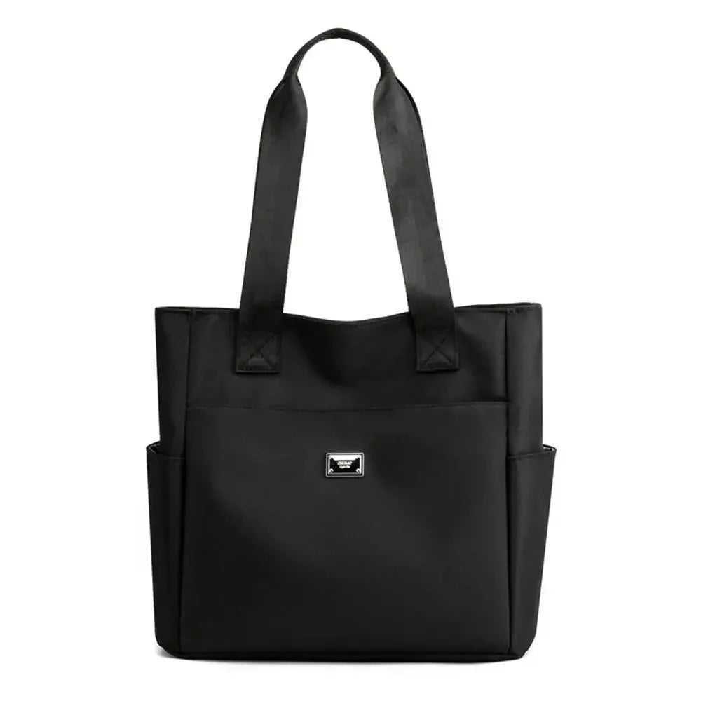 A black nylon shoulder tote bag with padded straps shown from the front.