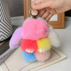 A cute plush rabbit charm with pink, purple, and yellow fur is shown attached to a gold keyring.