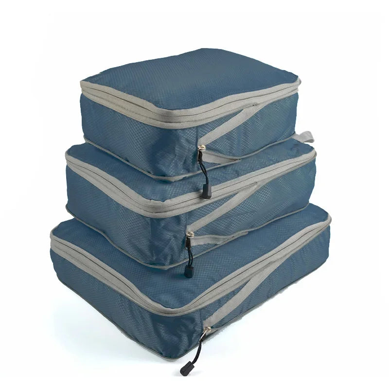 A set of three navy blue and gray reusable compression packing cubes stacked on a white background.