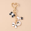 Gold enamel heart keychain featuring a black and white bow and a white high-heeled shoe charm