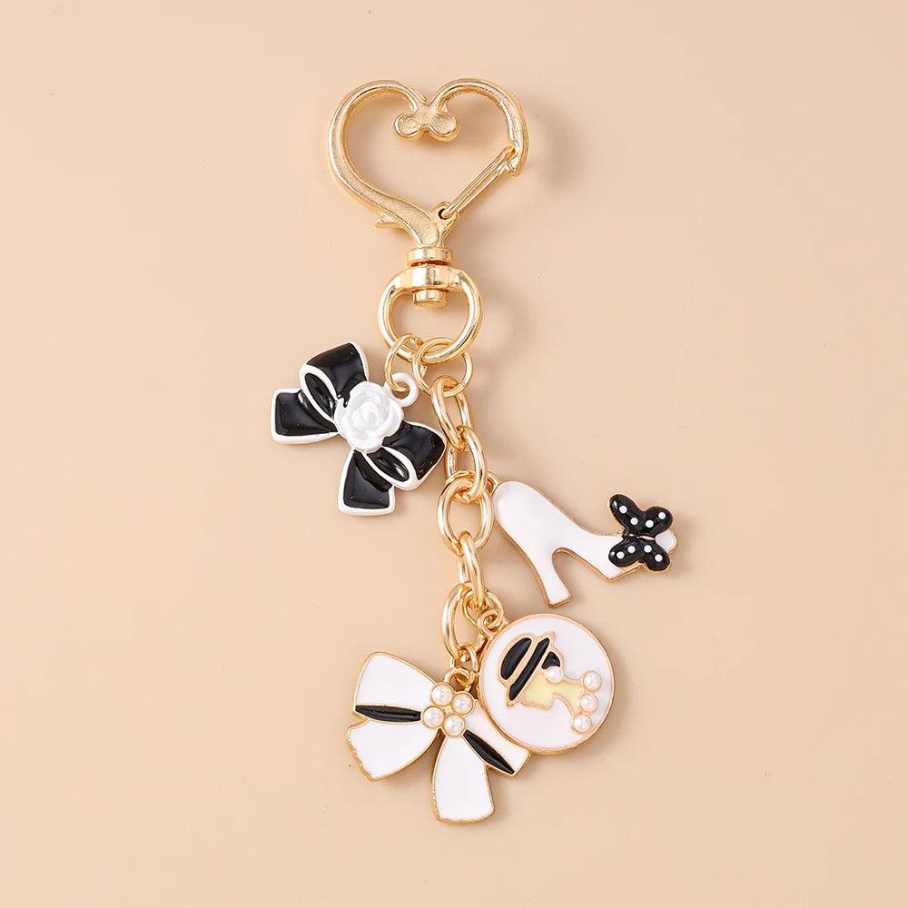 Gold enamel heart keychain featuring a black and white bow and a white high-heeled shoe charm