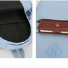 A light blue durable nylon commuter backpack showing the interior compartment and an exterior leather wallet.