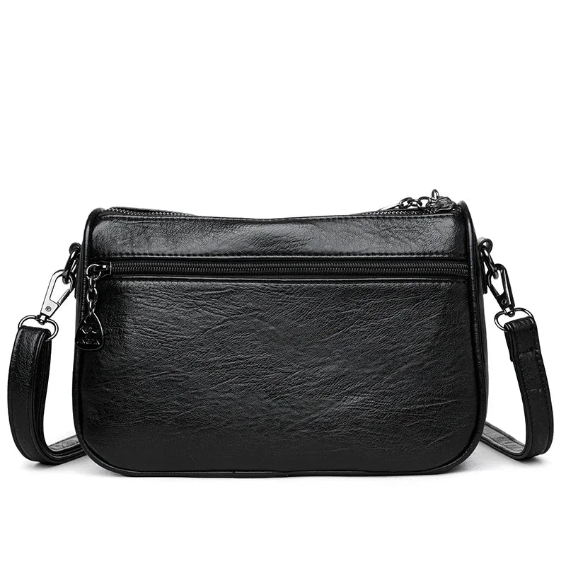 Bolso cruz de cuero negro moderno para mujer con cierre de cremallera y correa de cadena.