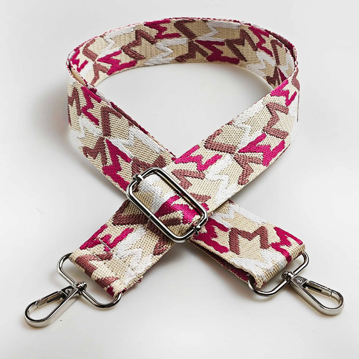 A beige and magenta jacquard patterned strap for an adjustable wide crossbody bag.