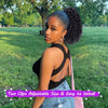 A woman models black kinky curly drawstring hair extensions against a green park background.