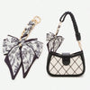 A black and white floral patterned adjustable bag strap with gold hardware.