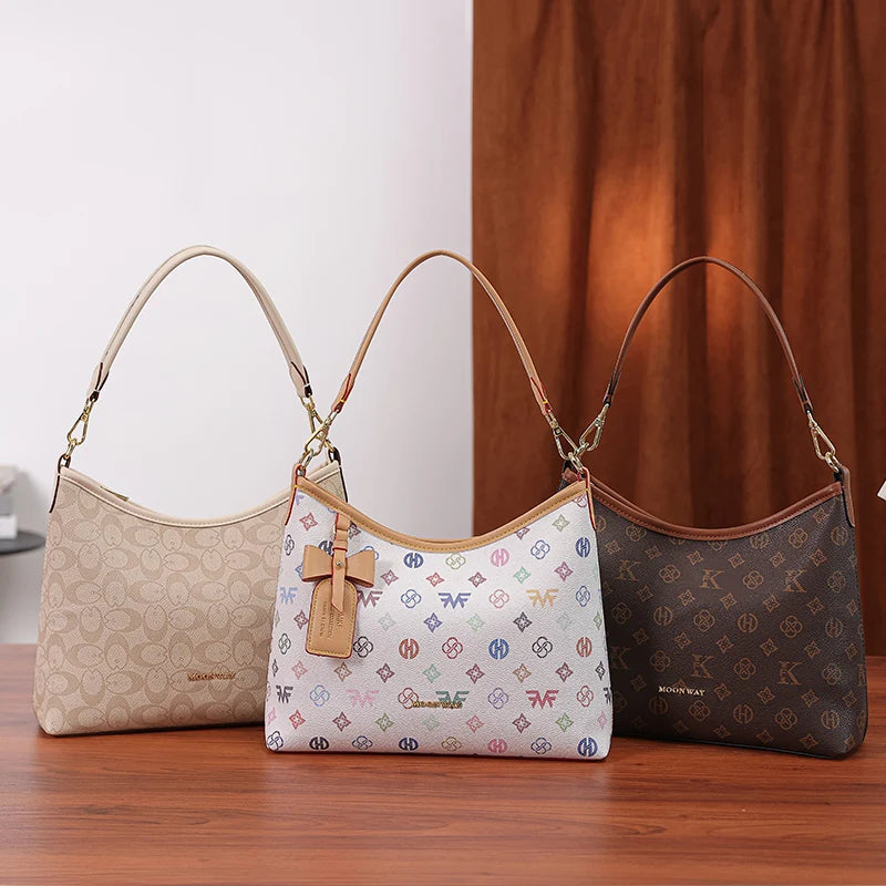 Three beige and brown leather tote bags with letter prints and bow accents displayed on a wooden surface.