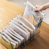 A hand is holding a clear mesh zipper pouch for storage, showing colorful fabric items inside.