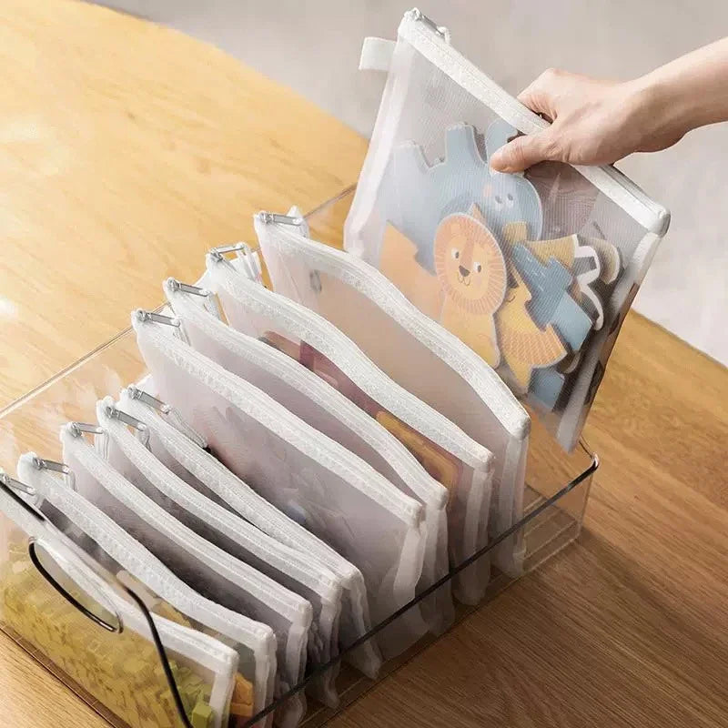 A hand is holding a clear mesh zipper pouch for storage, showing colorful fabric items inside.