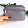 A hand holds a gray PU leather mini wallet with a silver keychain against a white background.