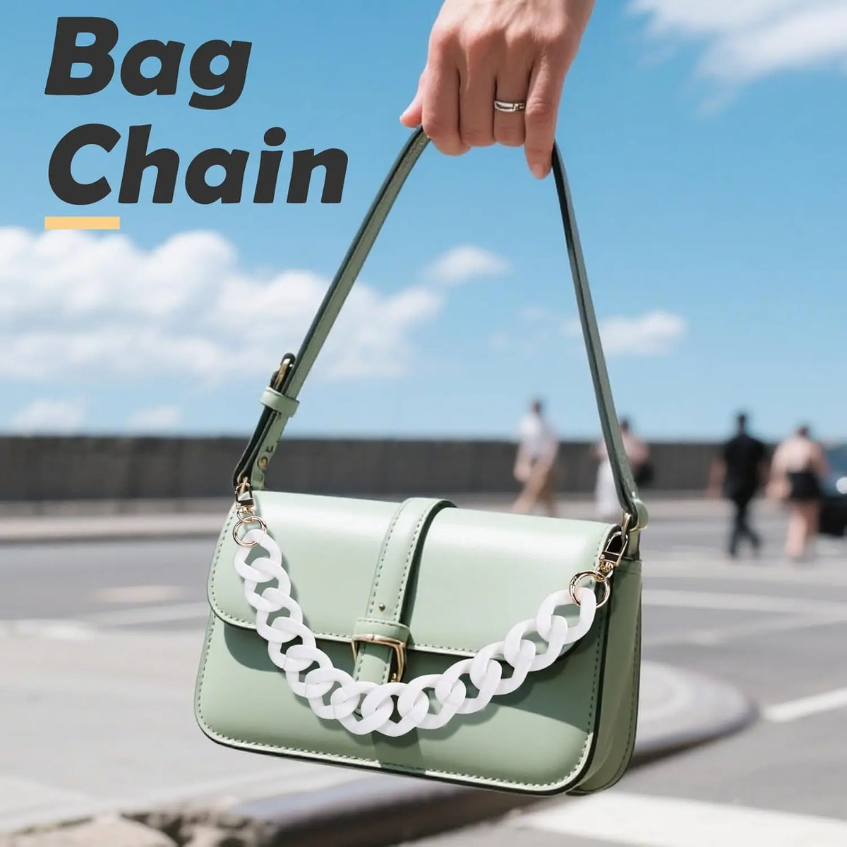 A hand holds a light green handbag with an acrylic chain strap against a bright sky backdrop.