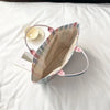 A striped transparent PVC tote bag is shown lying on a white sheet with a small bowl nearby.