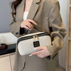 A woman holds a beige large capacity travel toiletry bag with gold accents and a tailored jacket.