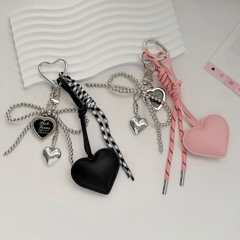 A collection of heart-shaped keychains and charms in black, silver, pink, and white cord on a white background.