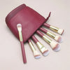 A maroon makeup brush storage case with several makeup brushes inside.