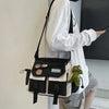 A woman is holding a black and white nylon crossbody shoulder bag with green charm.