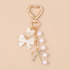 Gold heart-shaped keychain featuring a pearl bow design for bags and keys