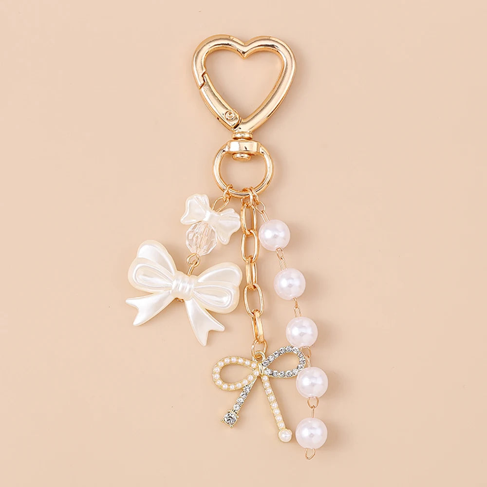 Gold heart-shaped keychain featuring a pearl bow design for bags and keys