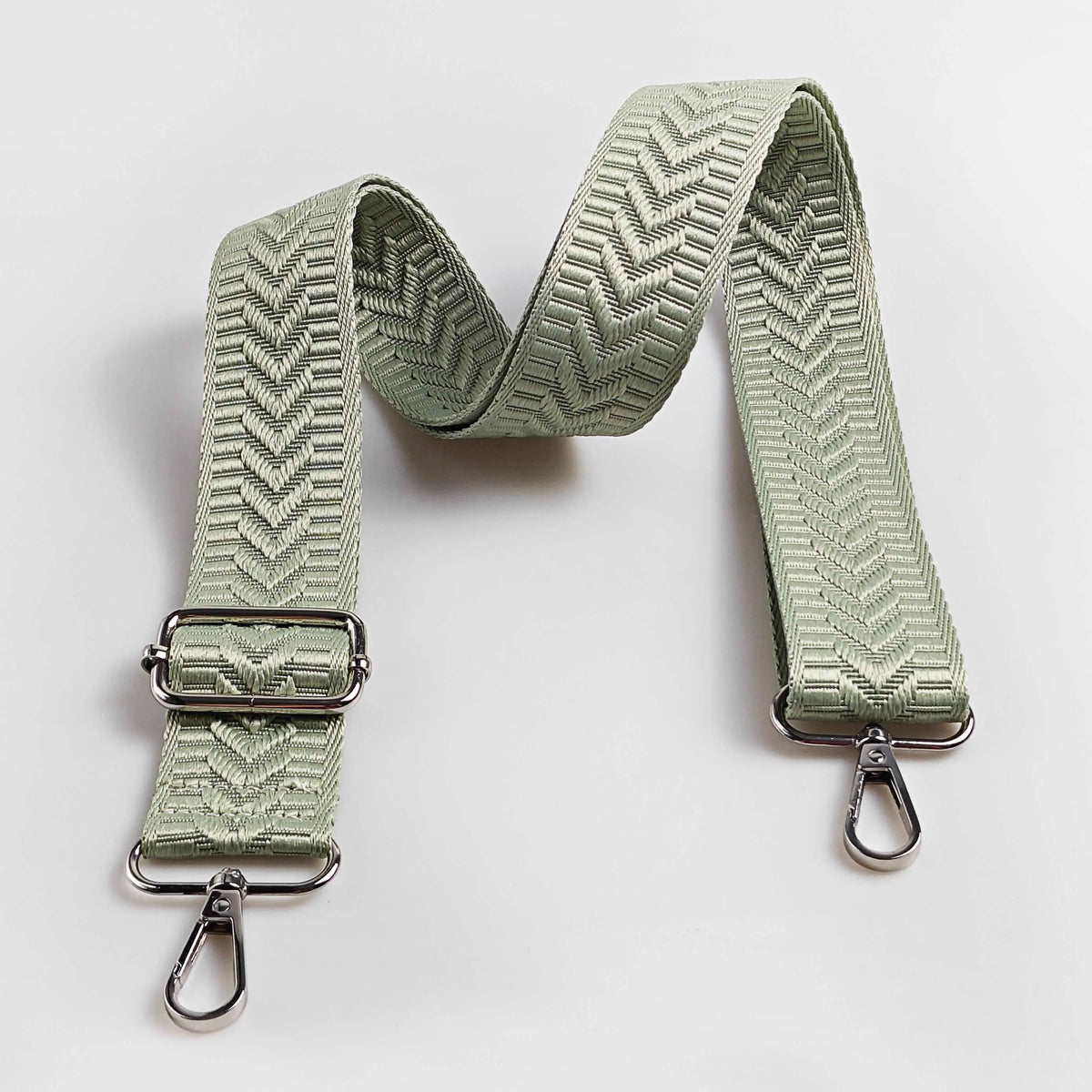 A light sage green adjustable handbag strap featuring an arrow jacquard pattern.