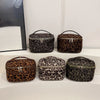 Four faux suede cosmetic bags in leopard print are displayed on a white surface.