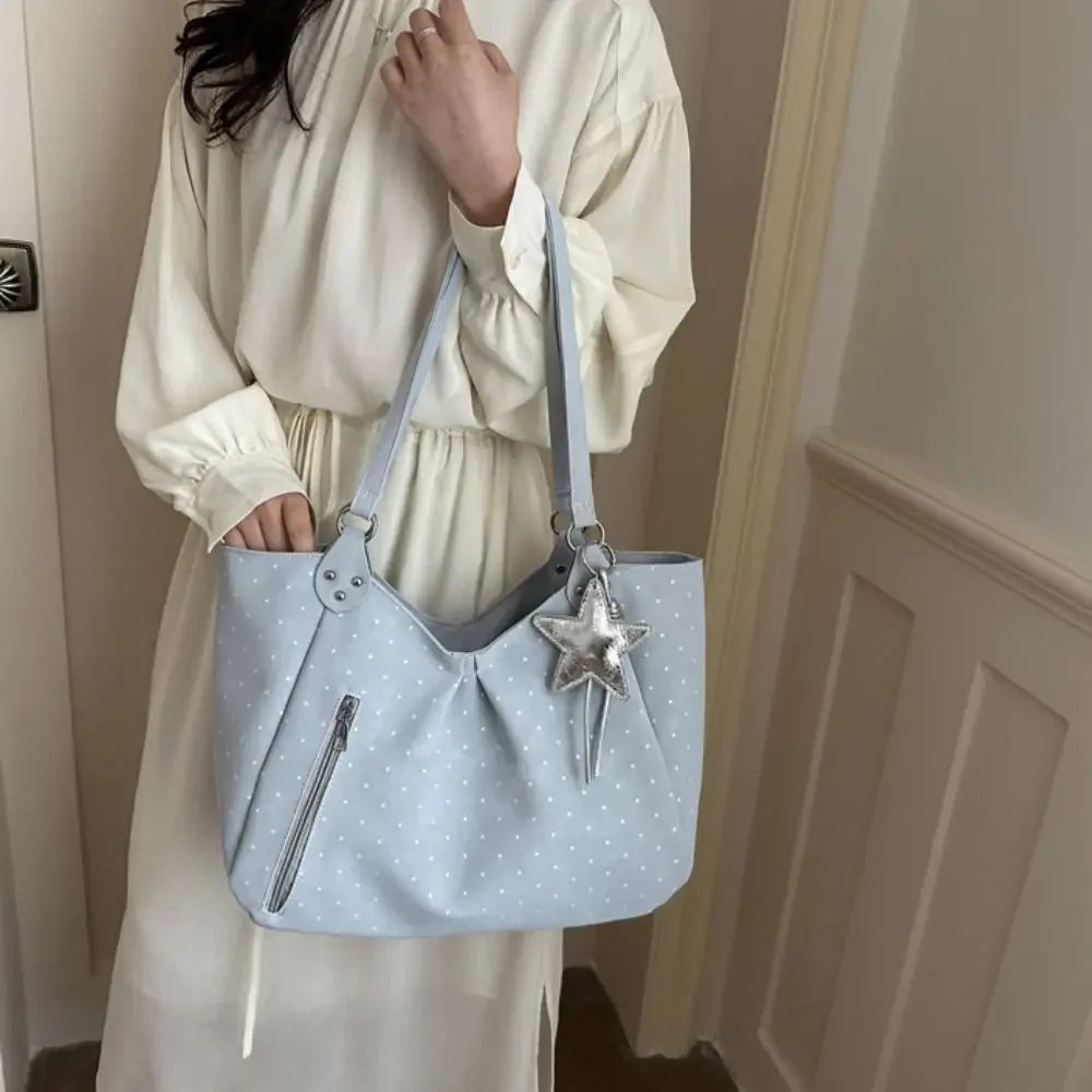 A light blue retro polka dot shoulder tote bag with silver star charm carried by a woman.