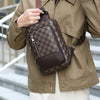 A man wearing a tan jacket holds a brown geometric pattern crossbody bag.
