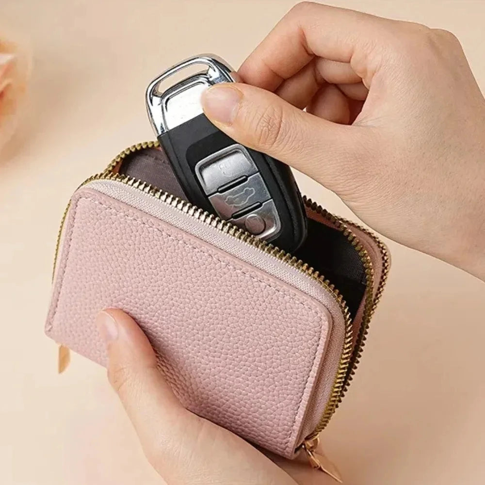 A hand is opening a pink zippered wallet with a gold-colored zipper, showing multiple card slots inside.