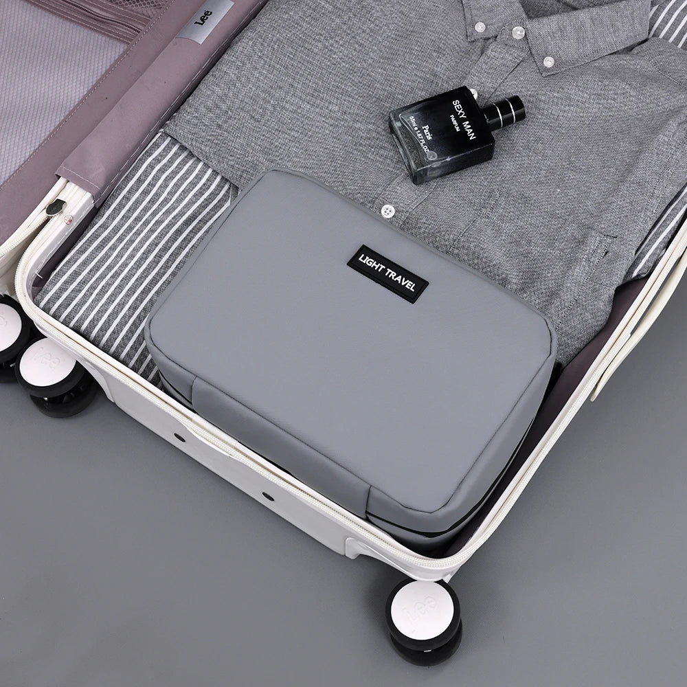 A gray portable waterproof travel toiletry bag is shown open inside a white suitcase with a striped lining and a small black 