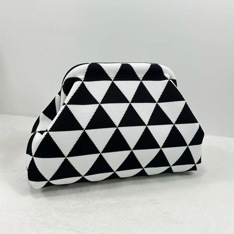 Pochette de plage en crochet à motif géométrique noir et blanc, sur une surface blanche.