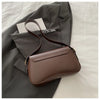 A brown vintage curved flap shoulder bag is shown resting on a gray blazer.