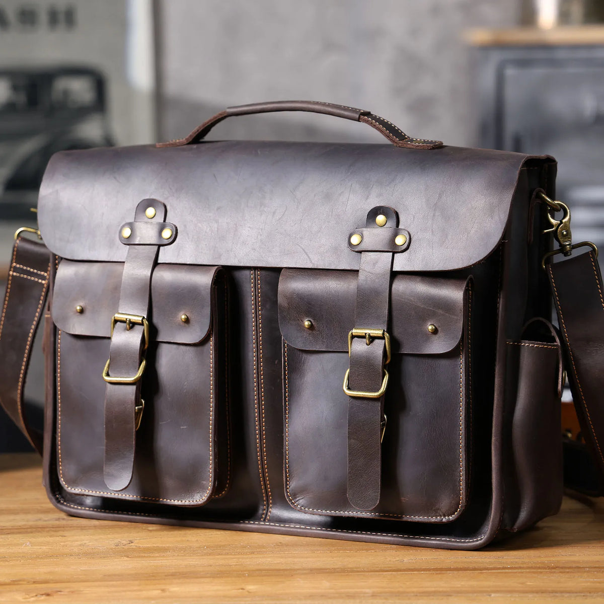 Maletín de cuero genuino vintage marrón oscuro para hombre con herrajes de latón sobre una superficie de madera.