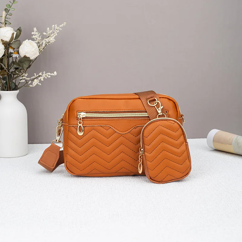 Orange gepolstertes Crossbody-Taschen mit weißem Krug und getrockneten Blumen im Hintergrund