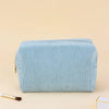 Light blue corduroy makeup organizer bag with an octagonal design shown on a beige surface.