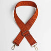 An orange woven strap with a maze pattern is shown crossed and laid flat.