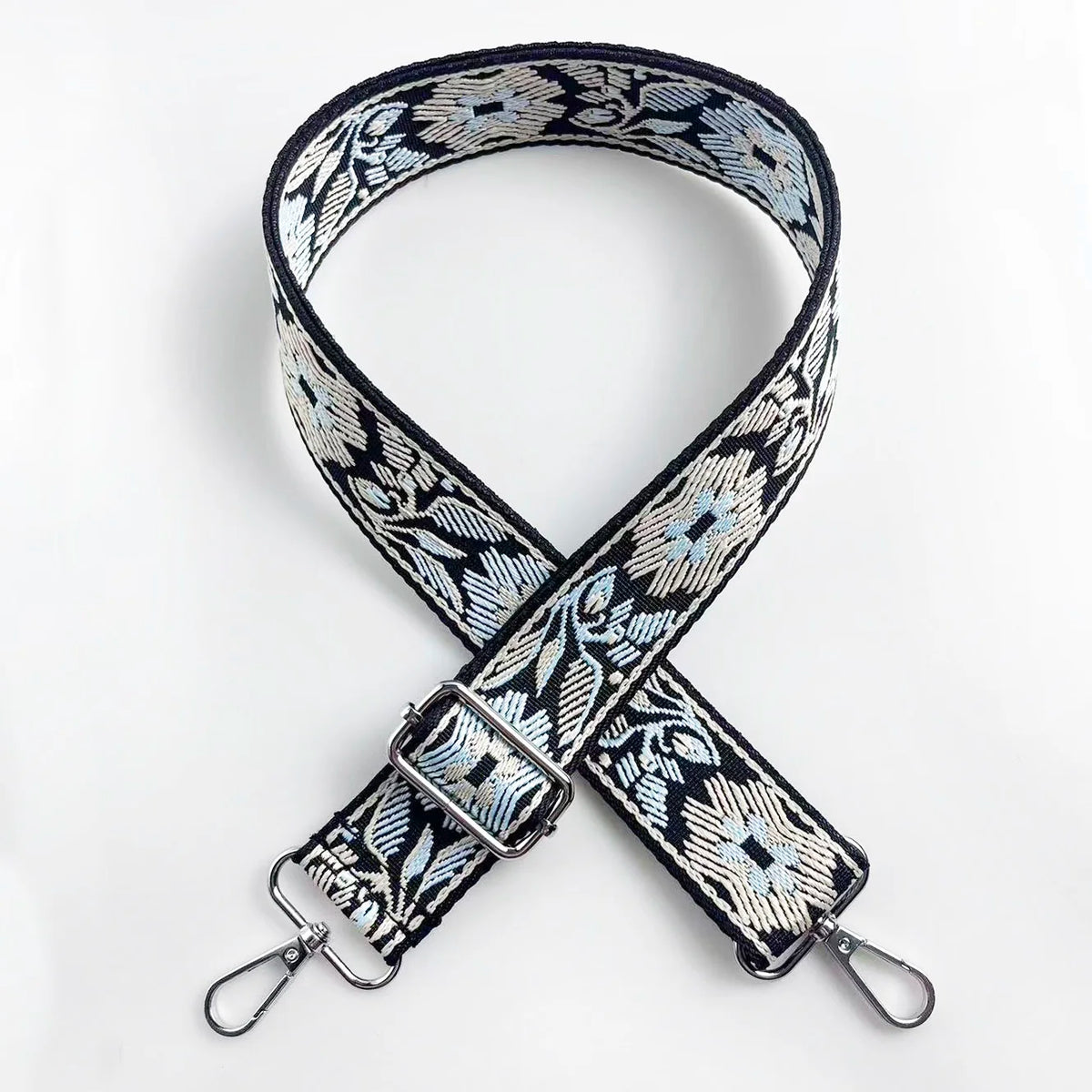 A black and white patterned jacquard strap for an adjustable crossbody bag.