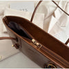 A brown leather tote bag with gold hardware and a zipper is shown open on a white background.