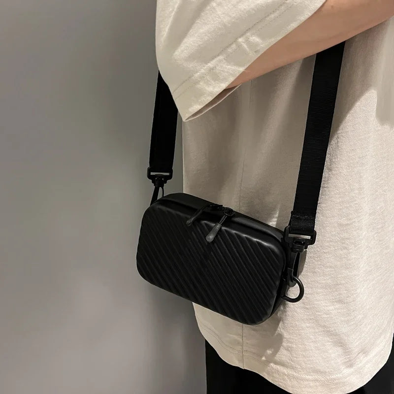 A black striped PU leather shoulder bag is shown hanging from a black strap against a light-colored shirt.