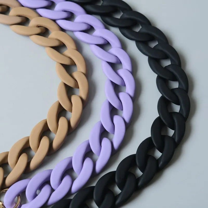 Three strands of adjustable long bag straps in beige, purple, and black coiled together.