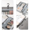 A gray travel toiletry bag with a hanging hook, showing various cosmetic and hygiene products inside.