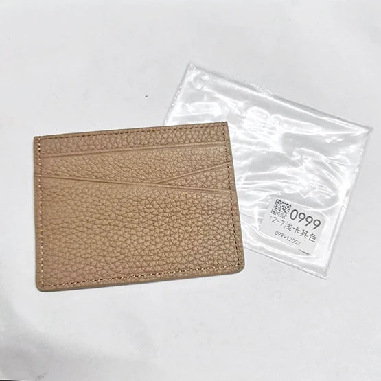 Porte-cartes en cuir véritable couleur camel avec gravure personnalisée, à côté de son emballage plastique transparent.