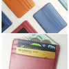 A collection of various colored slim PU leather mini wallets and card holders displayed on a white surface.