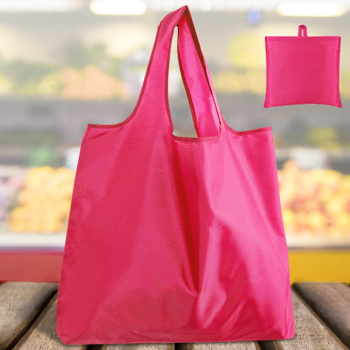 A bright pink reusable foldable grocery tote bag is shown in a close-up view.