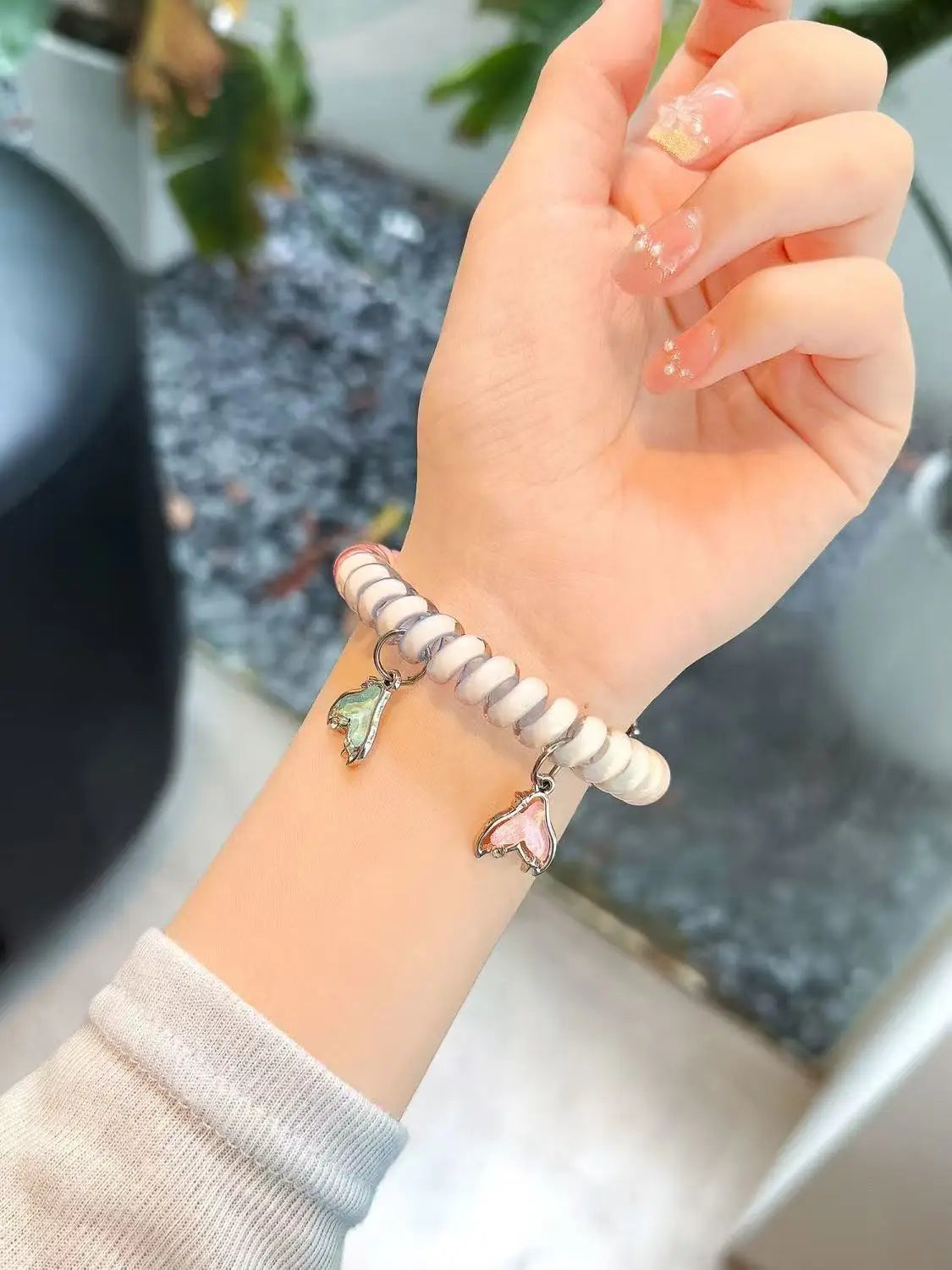 A hand is wearing a beige and white striped replacement elastic watch strap for a Huawei band.