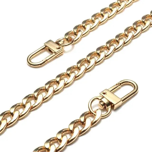 A close-up of a gold-toned stainless steel diamond-cut curb chain bag strap.
