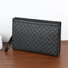 A black leather wallet or clutch with a textured pattern resting on a wooden surface.