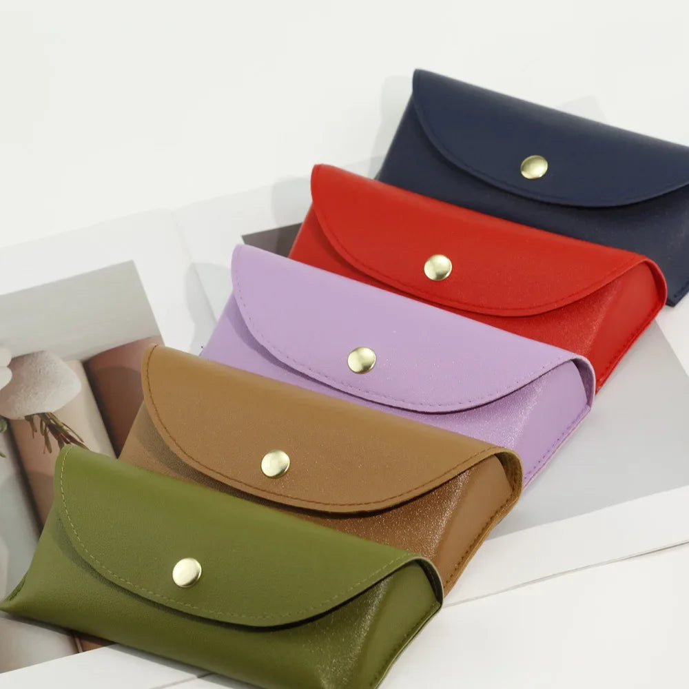 A collection of five PU leather hard shell sunglasses cases in various colors including navy blue, red, purple, olive green, 