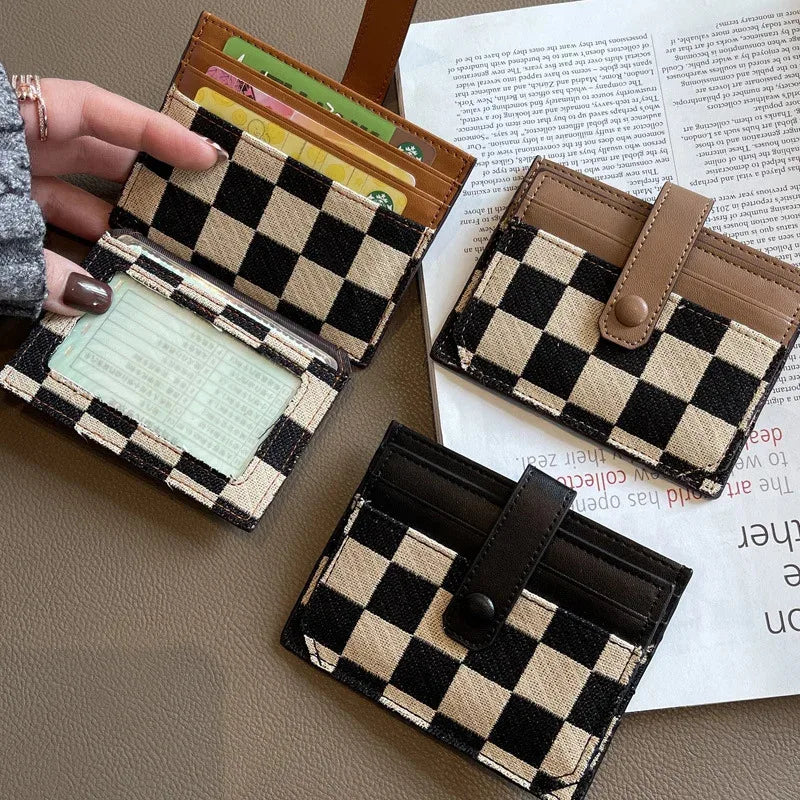 A collection of checkered PU leather mini card wallets in brown and black patterns resting on a light-colored surface.