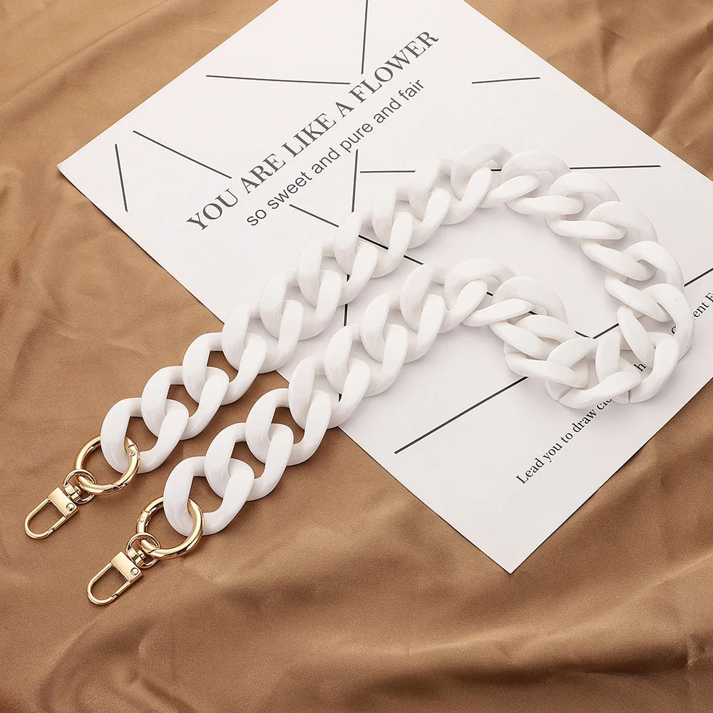 A white acrylic handbag strap chain is laid across a brown paper with black text.